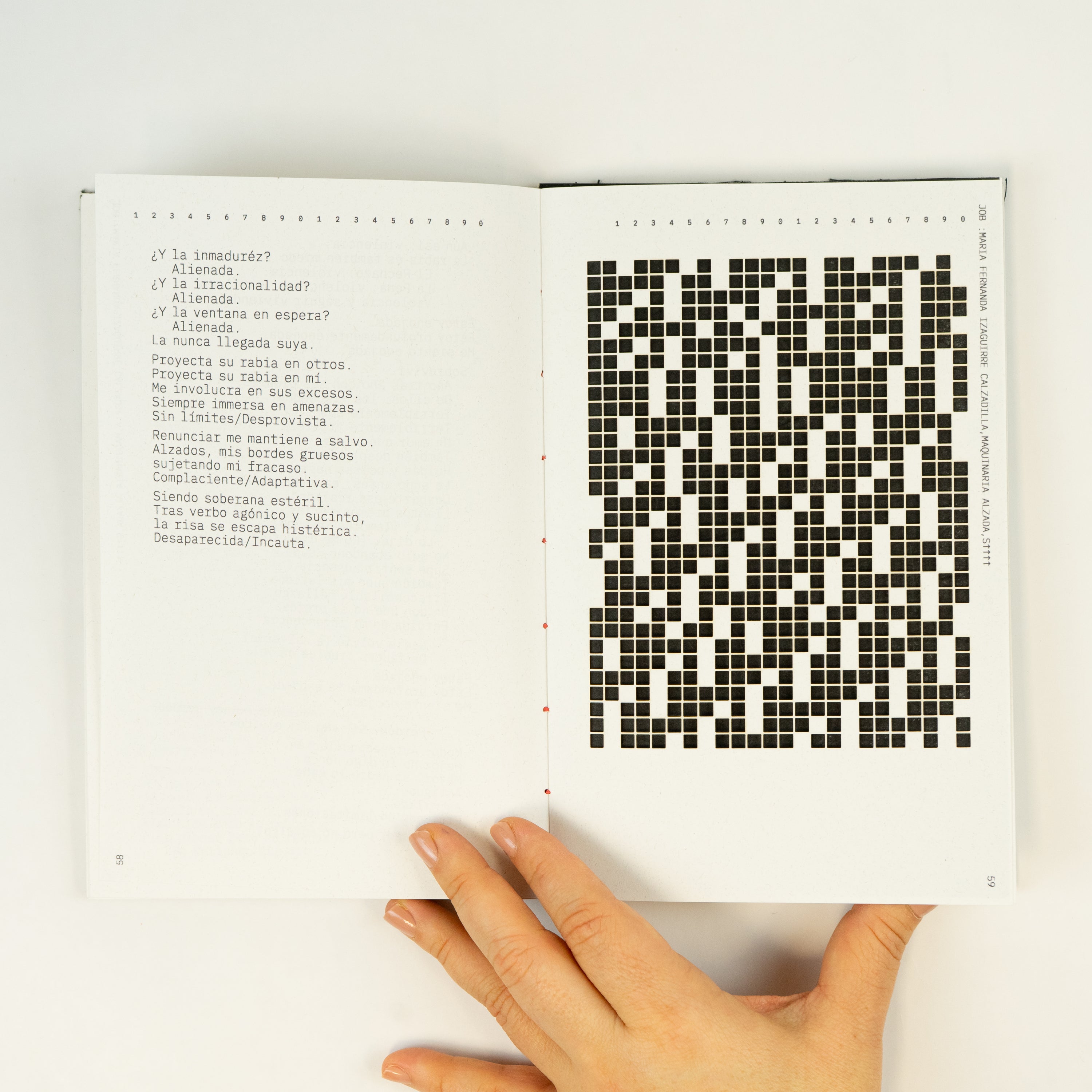 Female hand holding an open book with a poem on one page and a black square grid on the other.