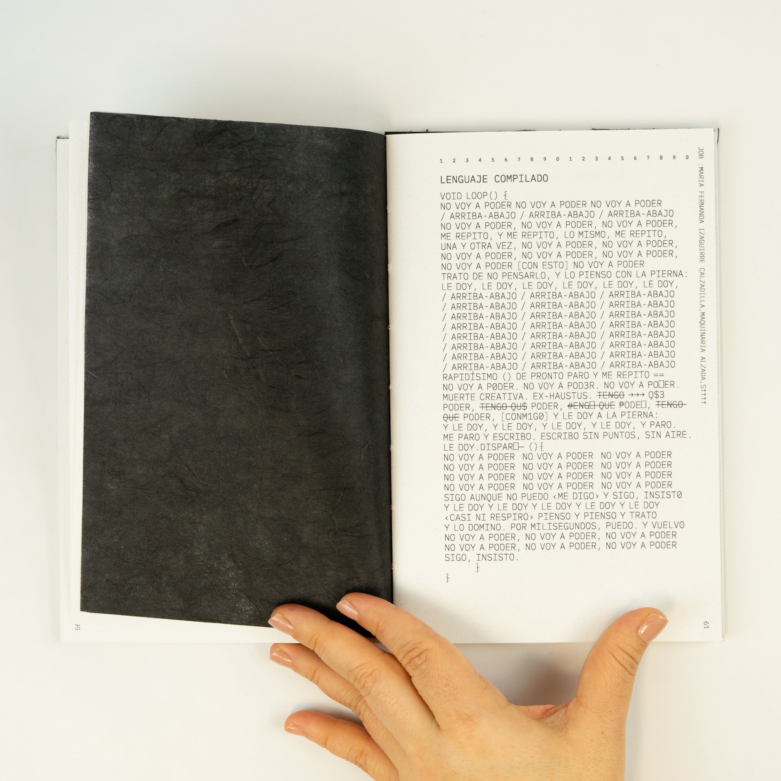 A female hand holding an open book with a black page and a poem on the other page