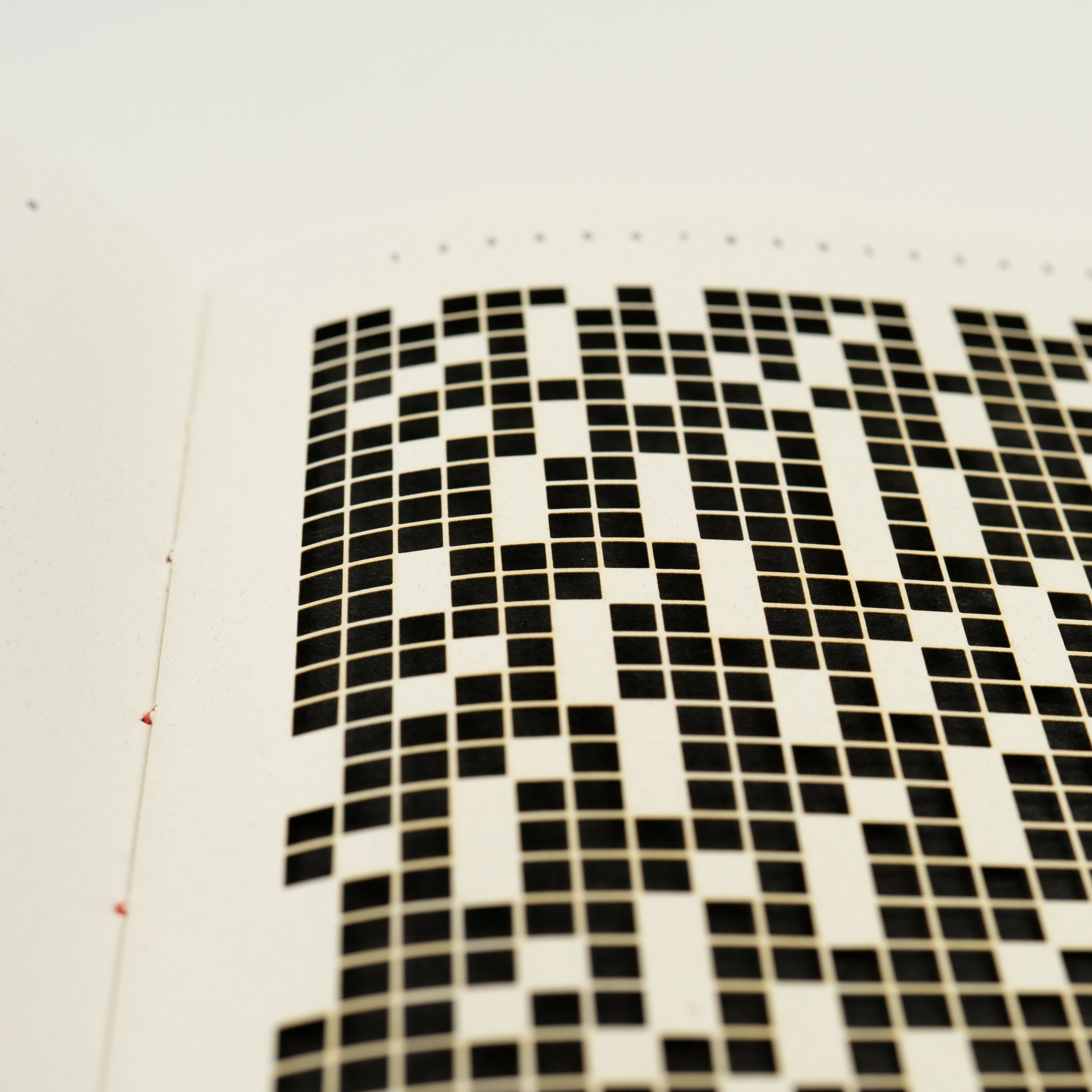 Close-up of a white page with a laser-cut square grid.