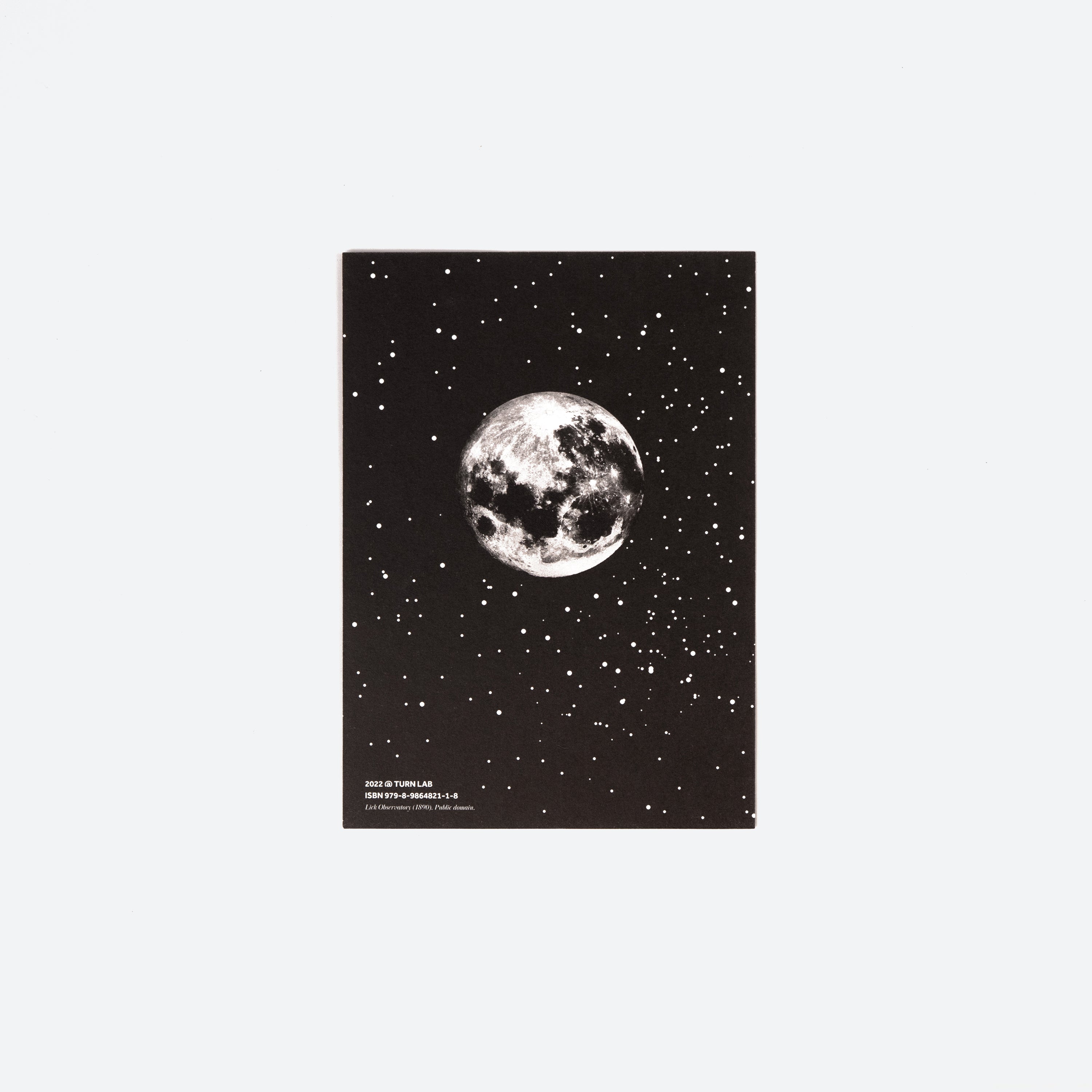 Back of a postcard with a black-and-white moon image against a starry black background.